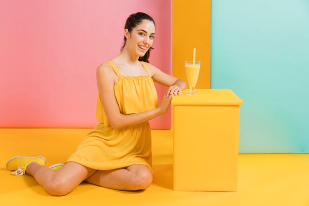 Mujer vestida de amarillo con un vaso de jugo