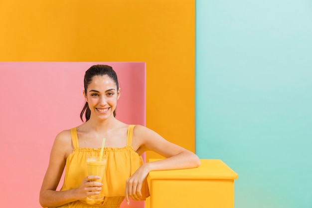 Foto gratuita mujer vestida de amarillo con un vaso de jugo