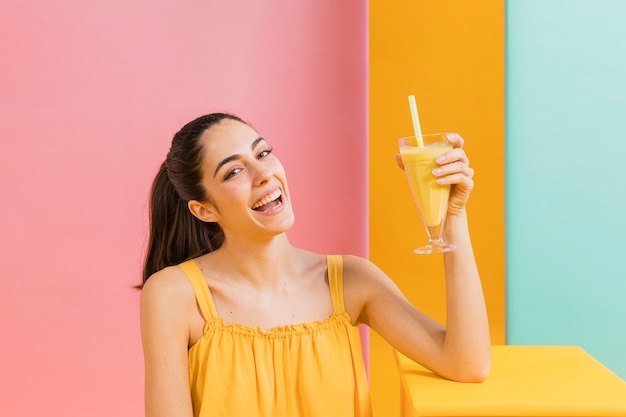 Mujer vestida de amarillo con un vaso de jugo