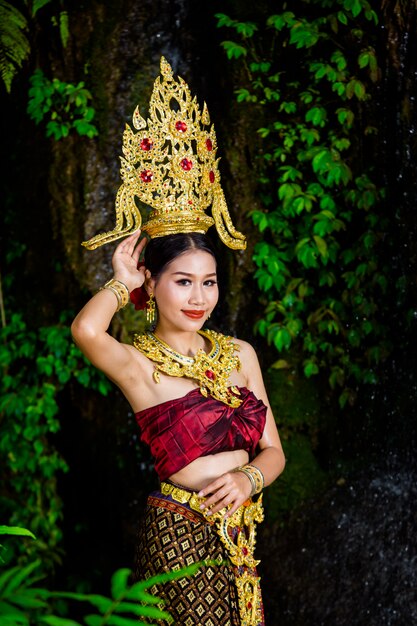 Una mujer vestida con un antiguo vestido tailandés en la cascada.