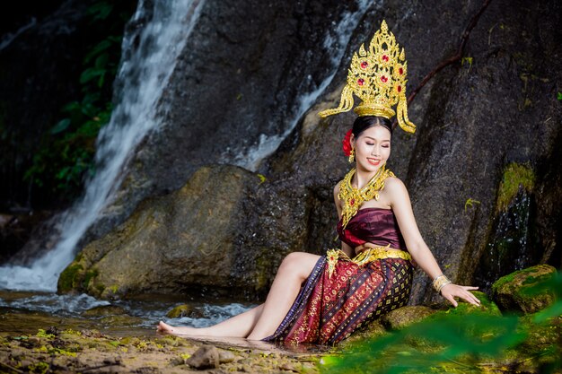 Una mujer vestida con un antiguo vestido tailandés en la cascada.