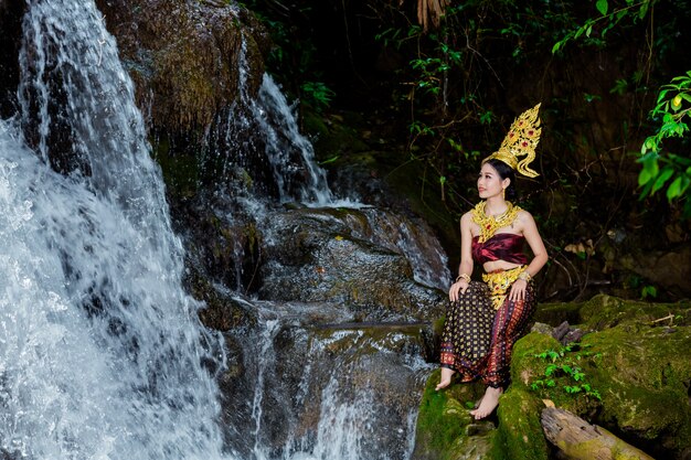 Una mujer vestida con un antiguo vestido tailandés en la cascada.