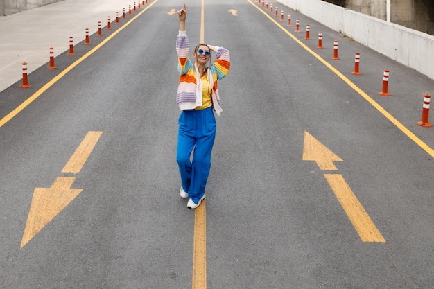mujer vestida de arcoíris bailando en la carretera
