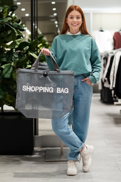 Mujer vestida casual que sostiene el bolso de compras