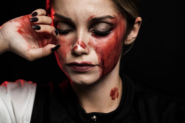 Mujer vestida con maquillaje sangriento sobre fondo negro