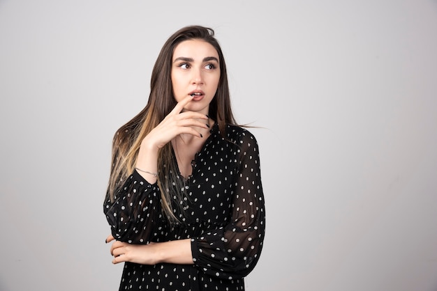 Mujer vestida de negro mirando en algún lugar de gris.