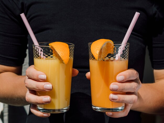 Mujer vestida de negro con vasos de jugo