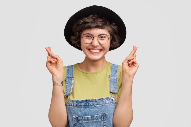 Mujer vestida con overoles de mezclilla y sombrero grande