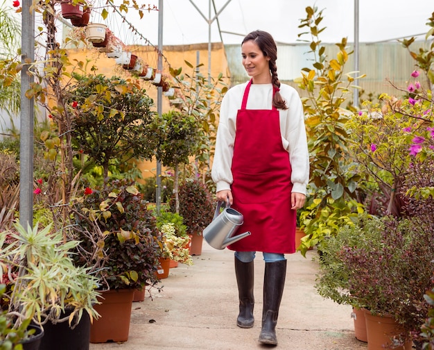 Mujer vestida con ropa de jardinería caminando en invernadero