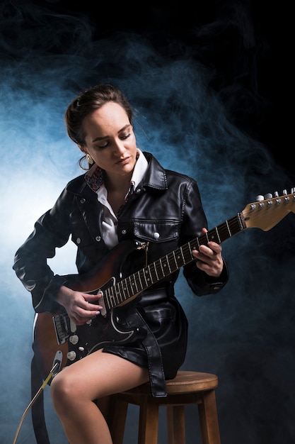 Mujer vestida con ropa de rock tocando la guitarra eléctrica