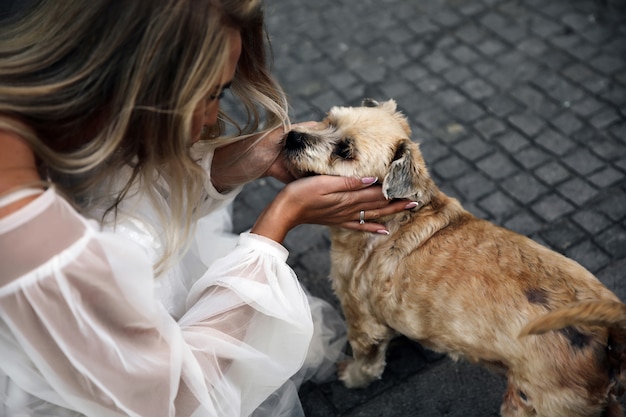 Mujer vestida con el vestido blanco encantador está mirando al lindo perro