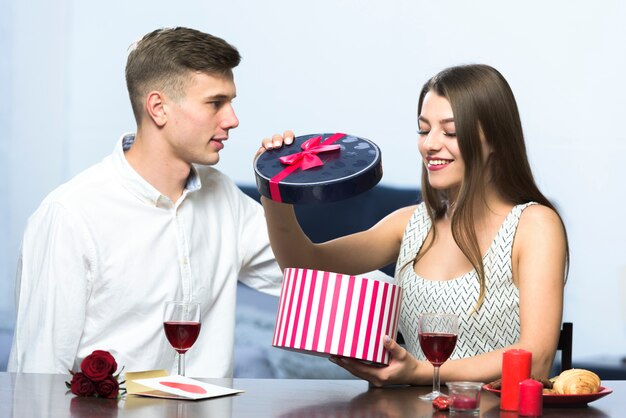 Mujer en vestido abriendo caja de regalo en mesa