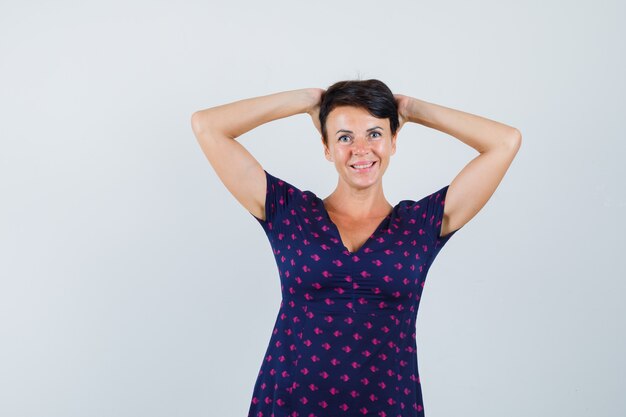 Mujer en vestido agarrando la cabeza con las manos y mirando alegre