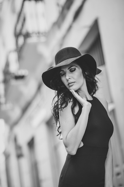 Foto gratuita mujer con vestido ajustado y un sombrero en blanco y negro