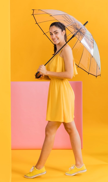 Foto gratuita mujer en vestido amarillo con sombrilla