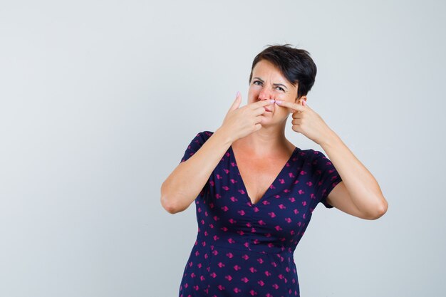 Mujer en vestido apretando su grano en la mejilla