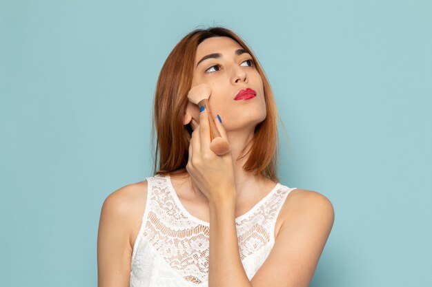 mujer en vestido blanco haciendo maquillaje