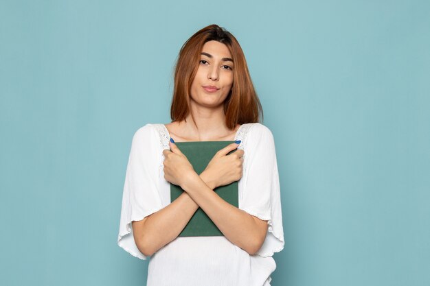 mujer en vestido blanco posando con cuaderno verde