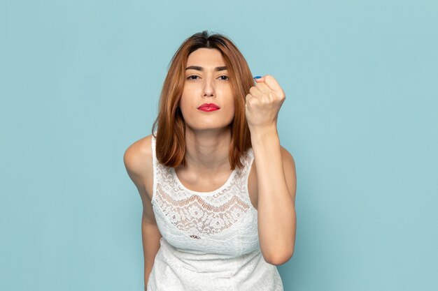 mujer en vestido blanco posando con expresión amenazante