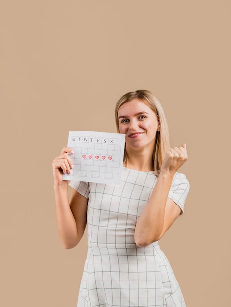 Mujer con un vestido blanco que muestra su calendario de menstruación