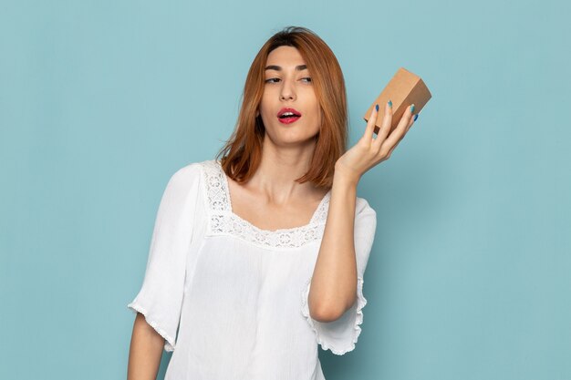 mujer en vestido blanco sosteniendo una pequeña caja de regalo