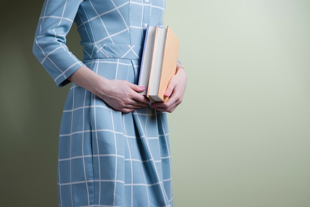 Mujer con vestido de cuadros sujetando dos libros