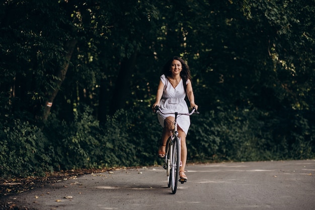 Mujer, en, vestido, equitación, bicicleta, en el estacionamiento