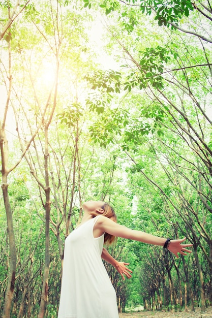 Foto gratuita mujer con vestido estirando los brazos en el bosque