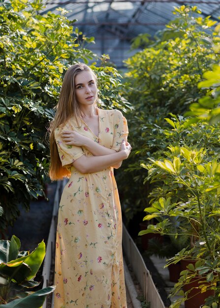 Mujer en un vestido largo de verano posando en un invernadero