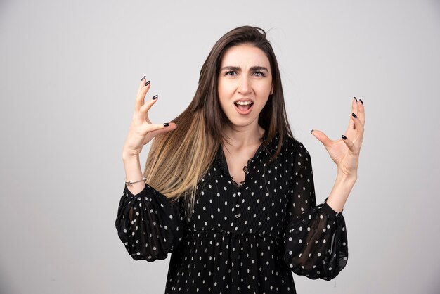 Mujer en vestido negro enojándose en gris.