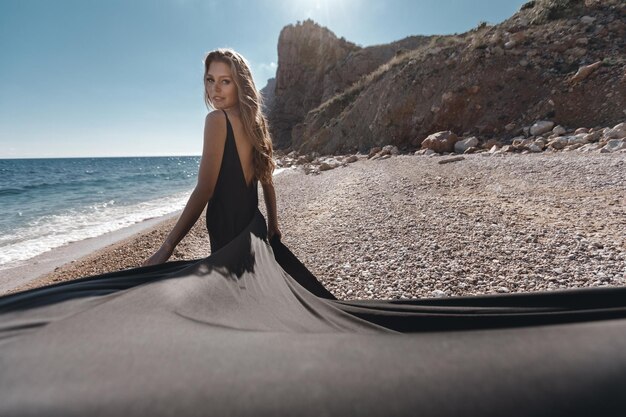 mujer con vestido negro largo cerca del mar