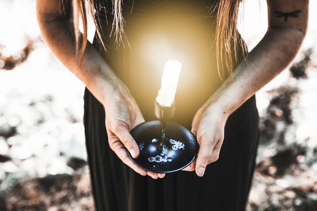 Foto gratuita mujer en vestido negro con vela encendida durante el día en el bosque