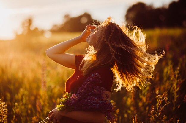 Mujer en vestido rojo gira en los rayos del sol de la tarde