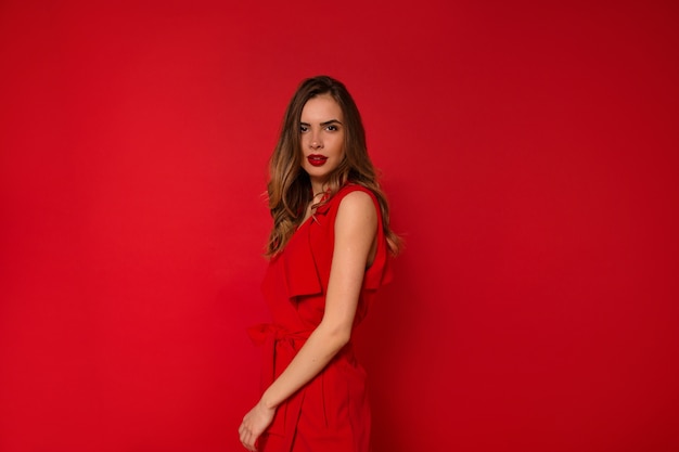 Mujer en vestido rojo de vacaciones con labios rojos posando