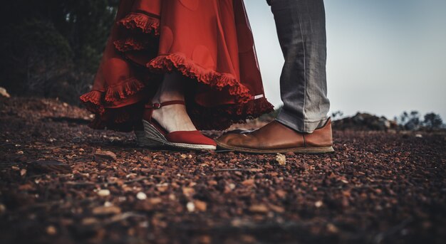 Mujer con un vestido rojo y zapatos delante de un hombre