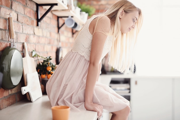 Mujer con vestido sentarse en la cocina