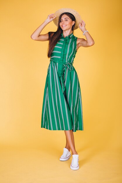 Mujer en vestido verde y sombrero sobre fondo amarillo