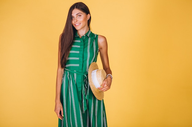 Mujer en vestido verde y sombrero sobre fondo amarillo