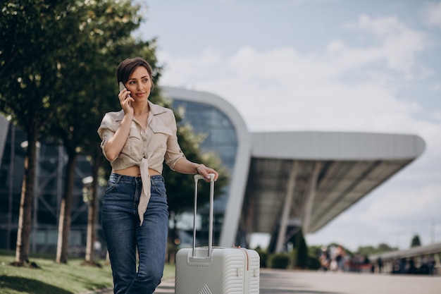 Mujer viajando con equipaje en el aeropuerto y hablando por teléfono