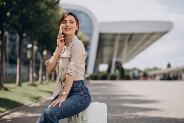 Mujer viajando con equipaje en el aeropuerto y hablando por teléfono