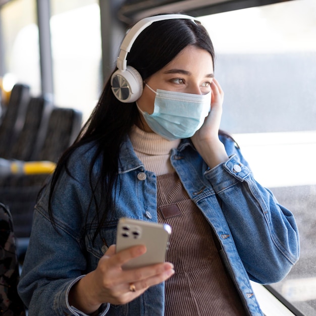 Mujer viajando con máscara y auriculares