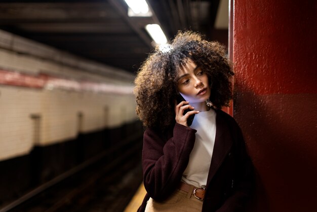 Mujer viajando con el metro en la ciudad y hablando por teléfono