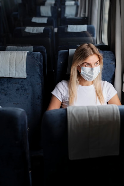 Mujer viajando en tren con máscara médica para protección