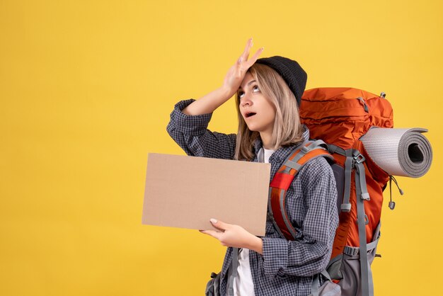 Mujer viajera cansada con mochila sosteniendo cartón