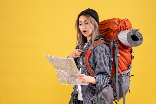Mujer viajera con mochila apuntando al lugar en el mapa