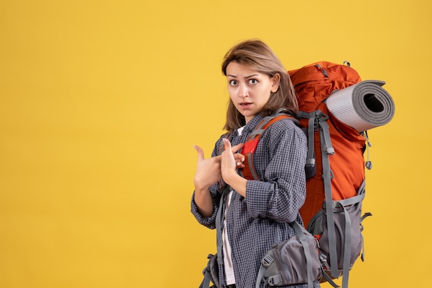 mujer viajera con mochila roja apuntando a sí misma