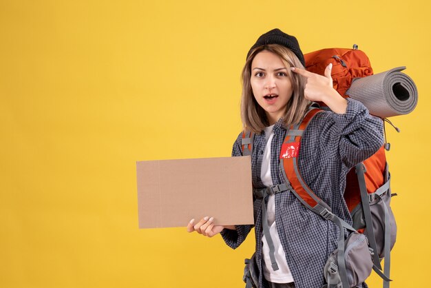 mujer viajera con mochila sosteniendo cartón