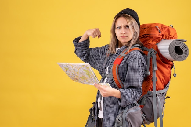 Mujer viajera con mochila sosteniendo mapa mostrando el músculo del brazo