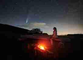 Foto gratuita mujer viajera sentada cerca de una fogata bajo el cielo estrellado de la noche