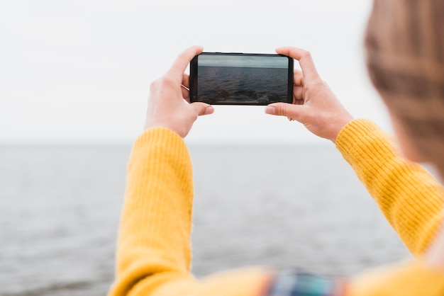 Mujer viajera tomando foto del mar